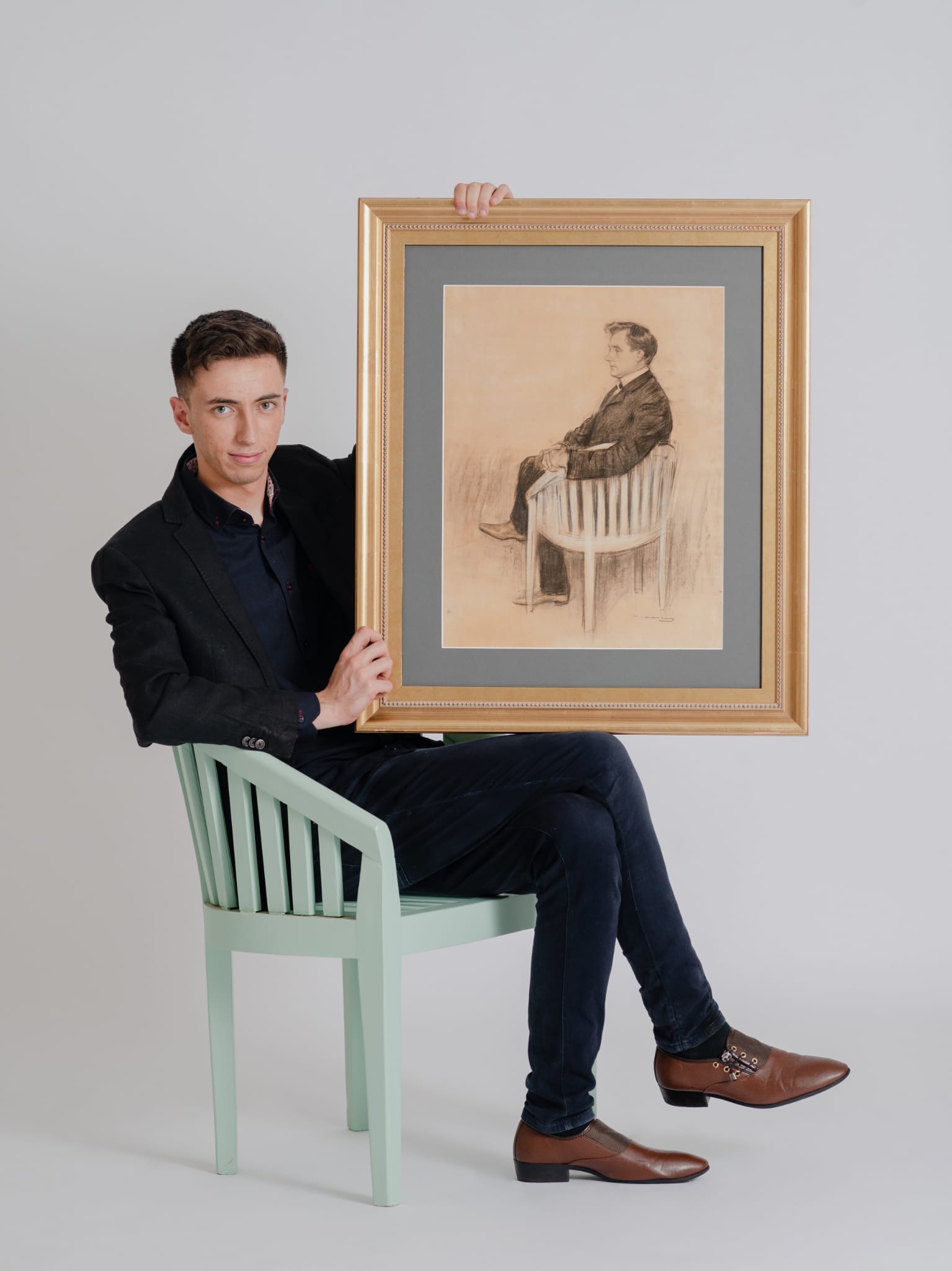 Adria Codina de la Casa del Coleccionista posa con un retrato de su antepasado Ramon Casas i Carbo serntado en la silla original que muestra el cuadro